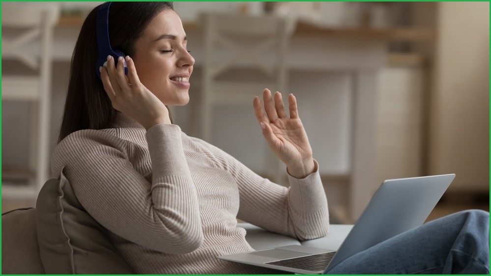 Woman relaxing with headphones on and a laptop in front of her