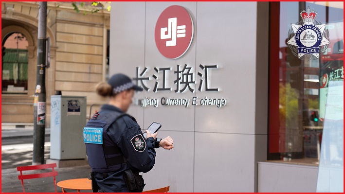 An AFP officer in front of a Changjiang Currency Exchange shopfront
