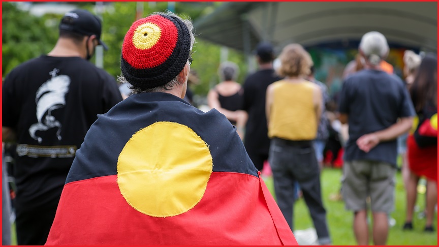 A person with an Aboriginal flag draped over their shoulders.