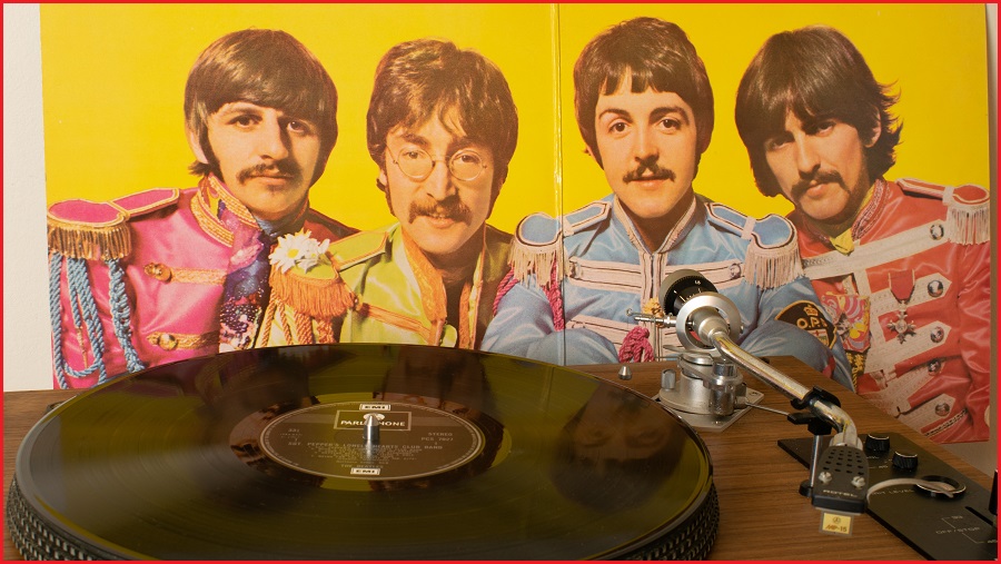 A vinyl record in front of a Beatles album cover