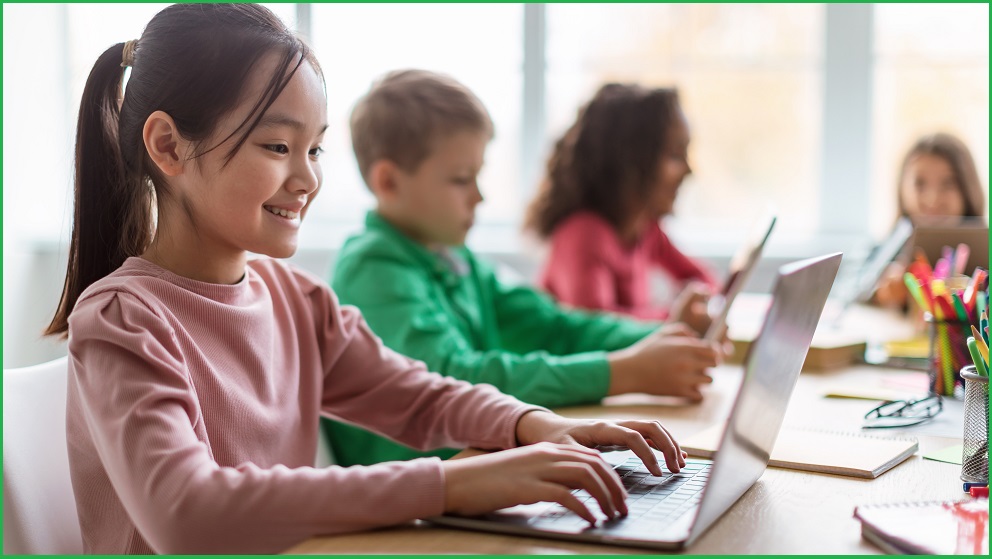 Children at laptops on a desk in school.
