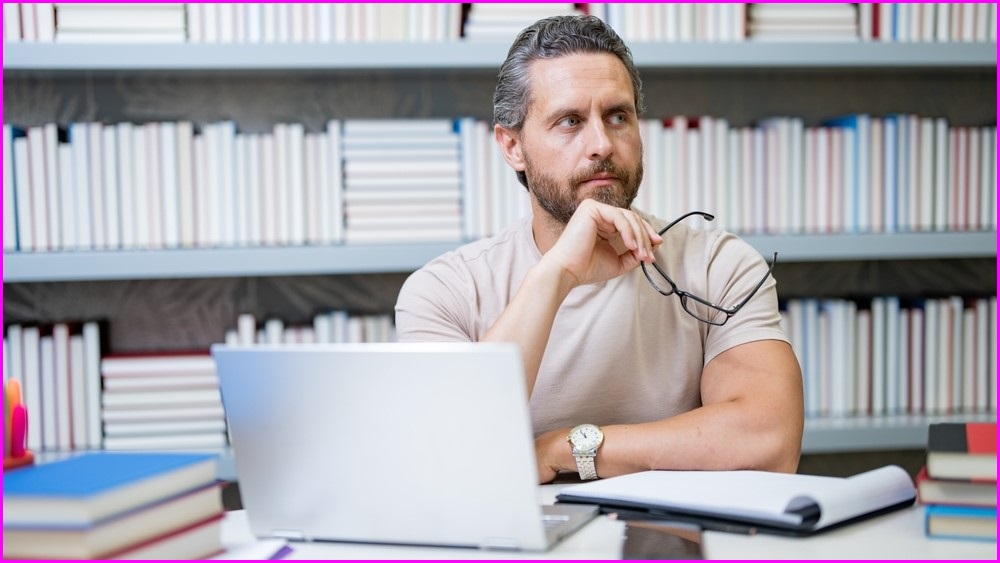 Man sitting at computer with shelves of books behind him