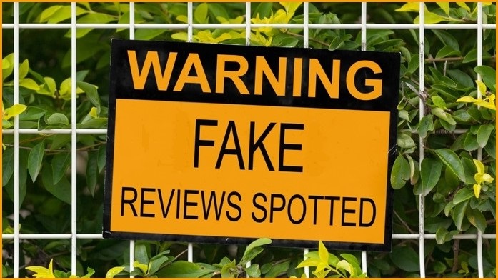 sign posted on fence that reads 'Warning: fake reviews spotted'
