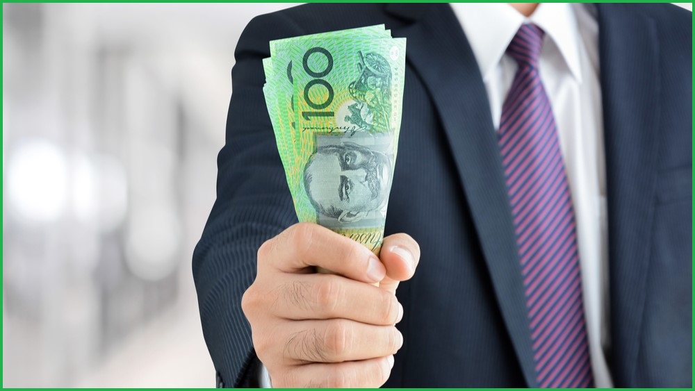 Man holding handful of Australian $100 notes