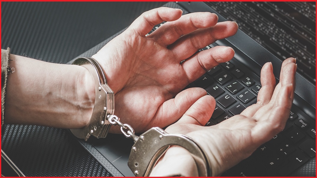 hands in handcuffs on a laptop keyboard