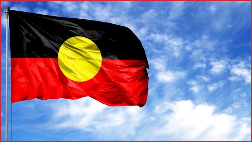 Thge Aboriginal flag against a blue sky background