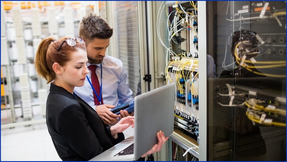 Man and woman on a laptop in a server room