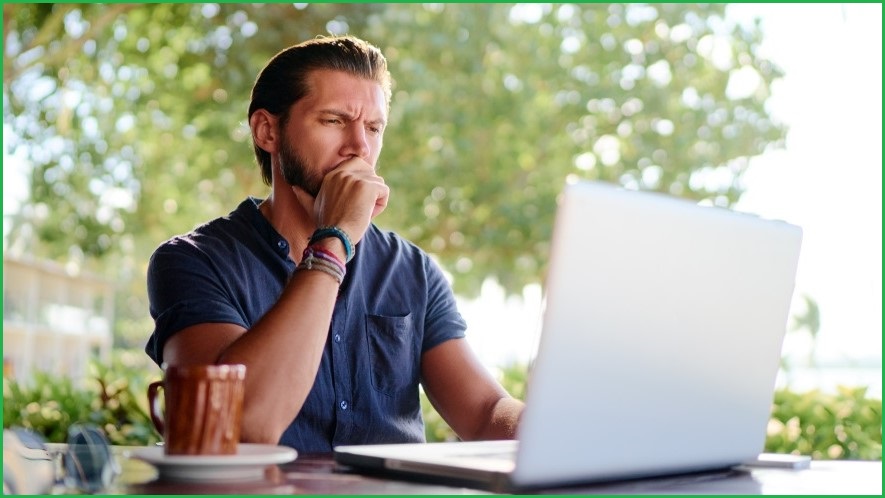 Man in rural setting looking thoughtfully at computer screen