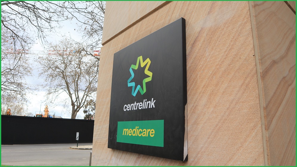 A centrelink sign on a sandstone building during a winter's day.