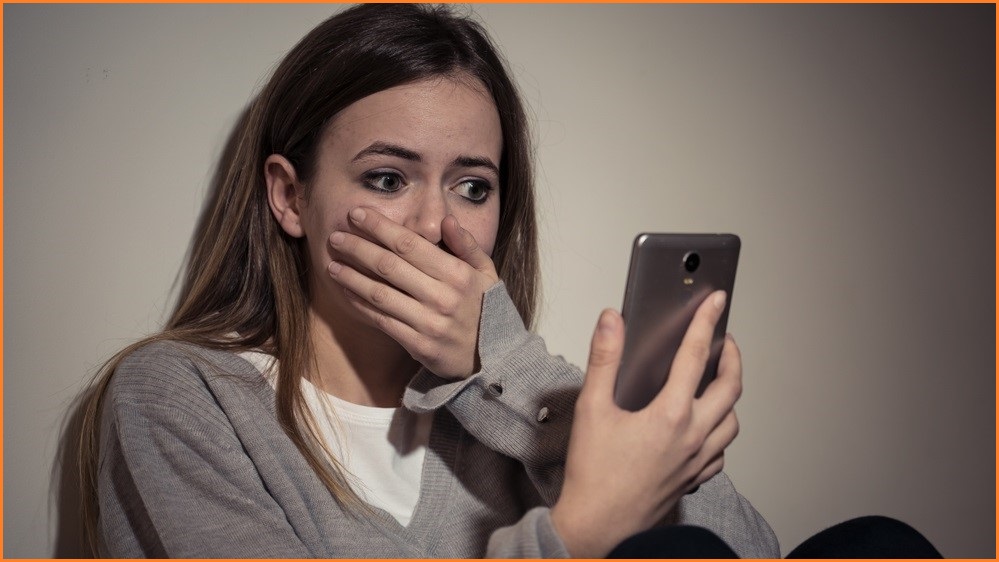 high school female looking at phone screen with shocked expression