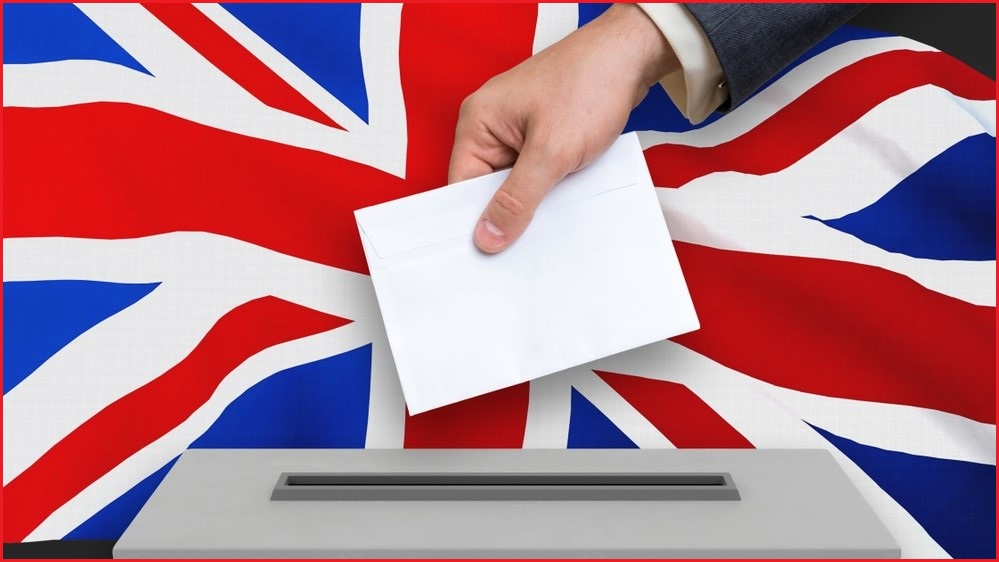 hand dropping paper into ballot box with uk flag background