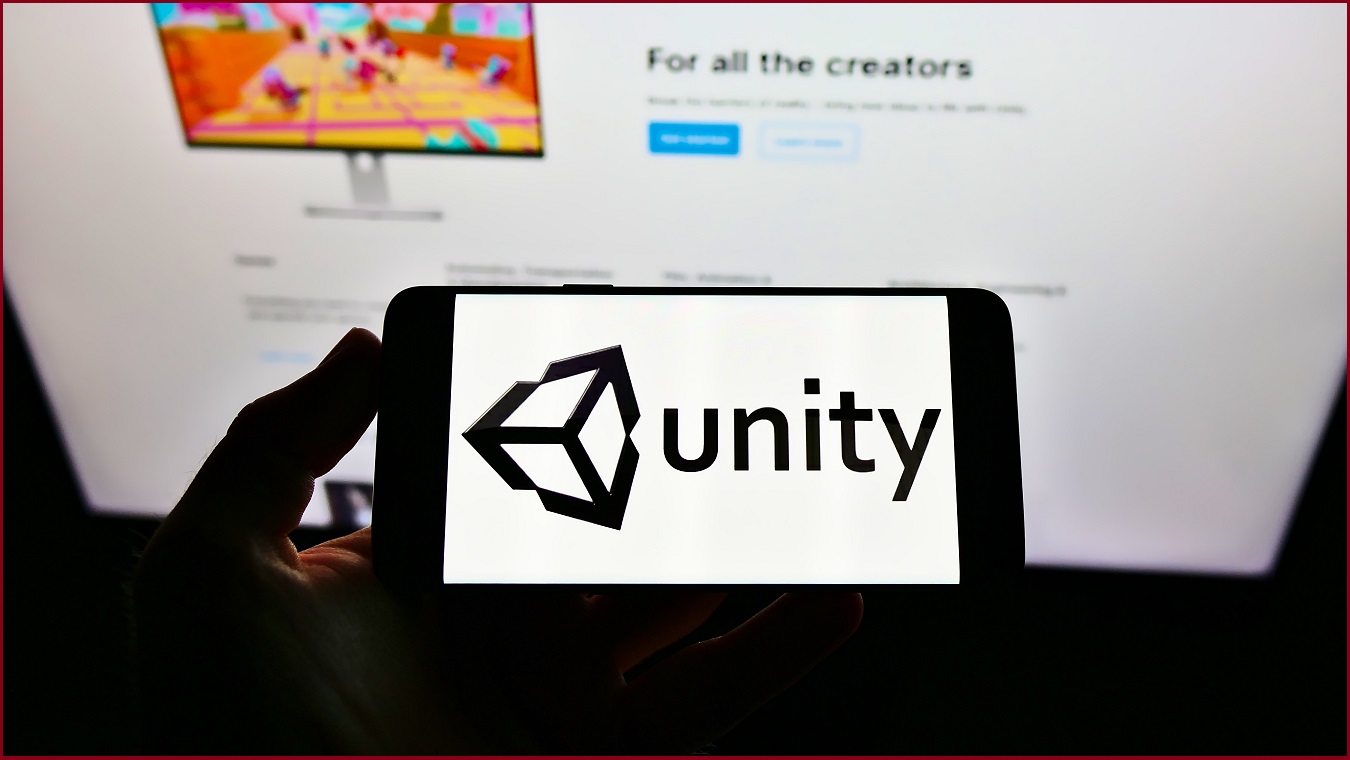 The Unity logo held up on a phone in front of the company's website.