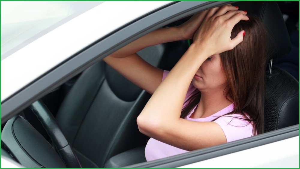 Woman sittting in car 's driver seat holding her head