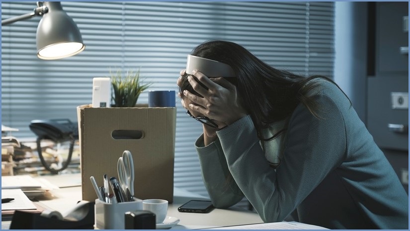 woman sitting at desk, despairing with hands face in hands