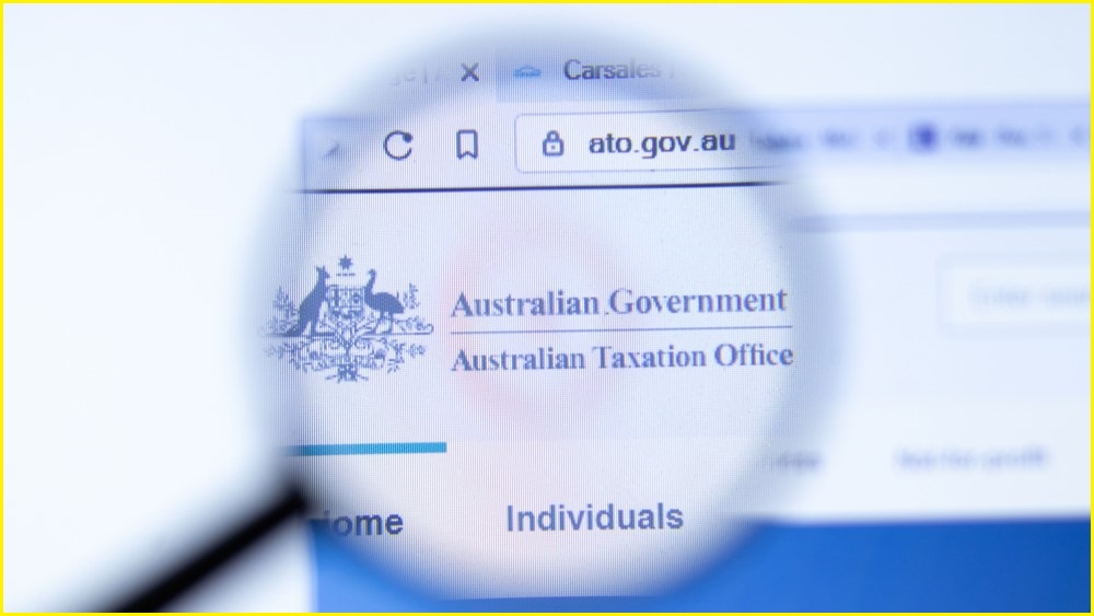 A close up of a magnifying glass examining the Australian government coat of arms on the Australian Taxation Office website.