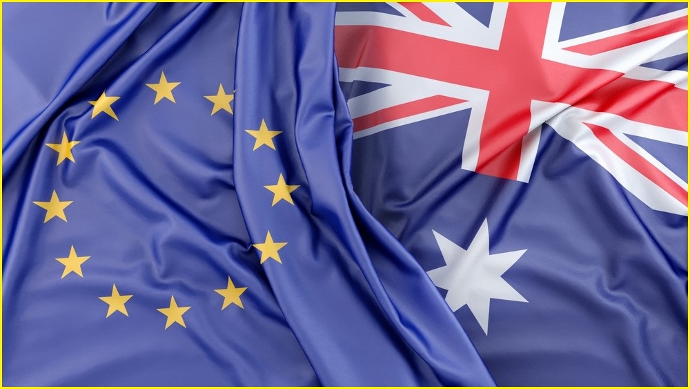 An Australian flag next to a European Union flag, close ups.