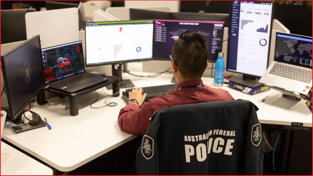 AFP officer working on computers at his desk.