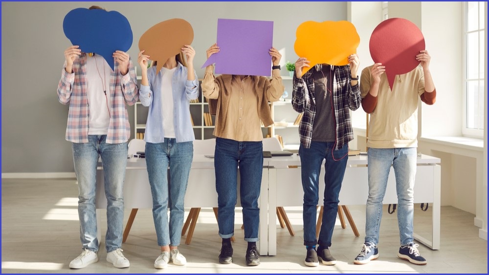 Five people standing in a row holding up empty caption-shaped cutouts