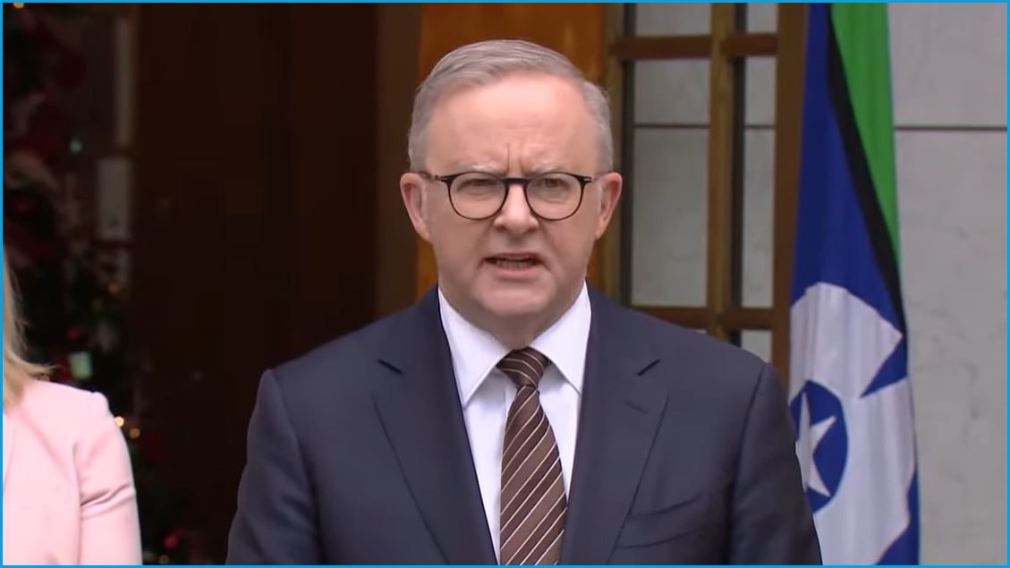 A close up of Anthony Albanese in a suit, tie and glasses giving a press conference.