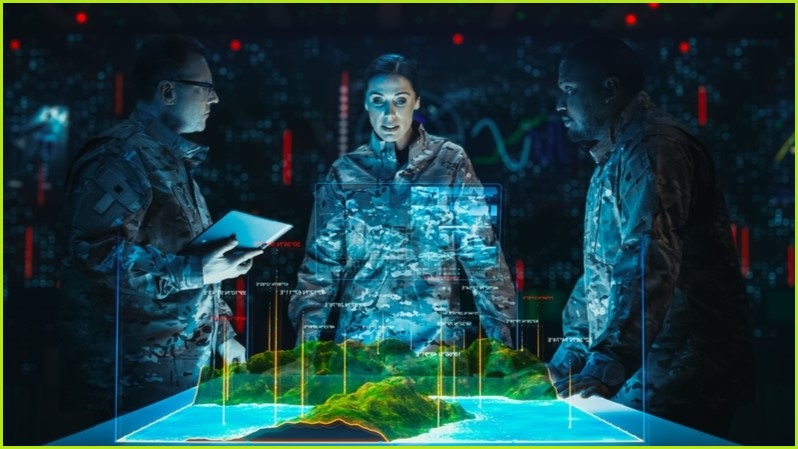 Three military personnel looking at a holographic map.