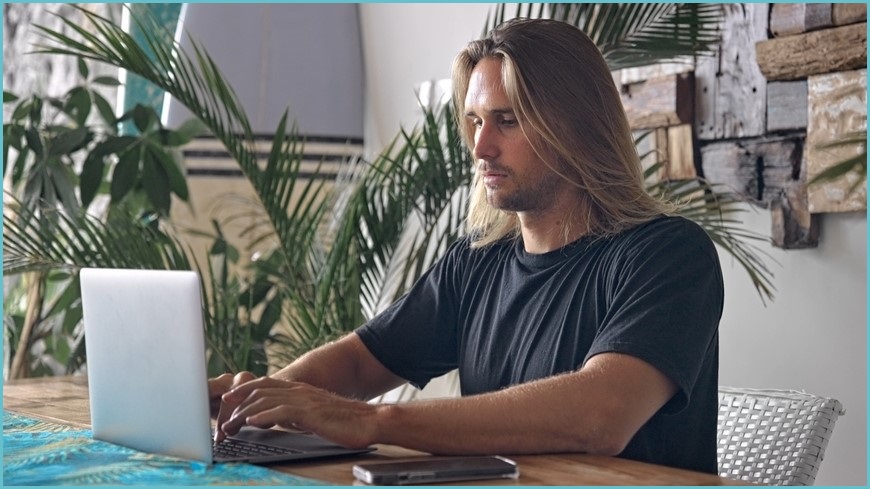 Man with long hair sitting at computer