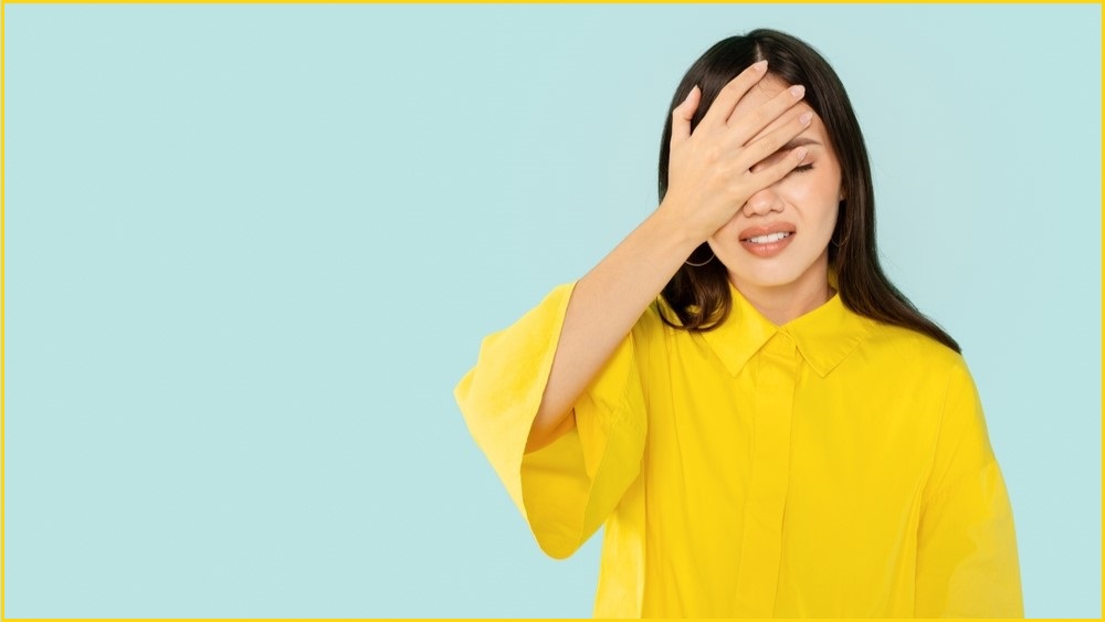 Woman in yellow top facepalming.