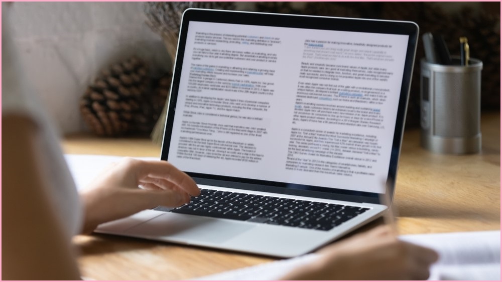 Woman typing on a keyboard with text on the screen.