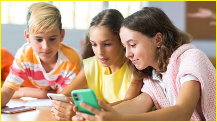 A group of three children looking at phone screens.