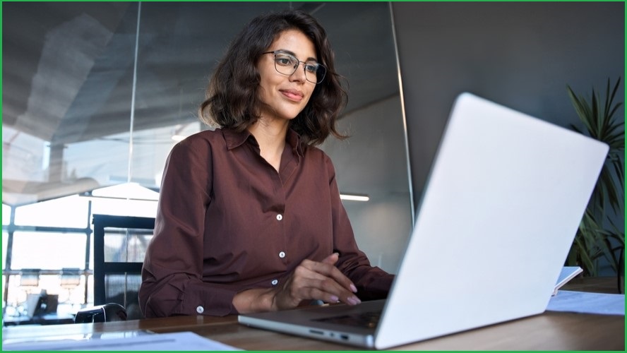 Woman sitting at computer, smiling.