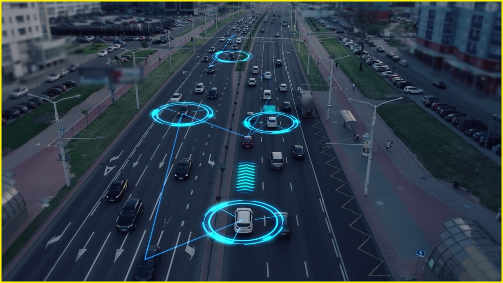 A wide aerial photo of cars on a highway, with some circled and connected to illustrate internet-connected vehicles.