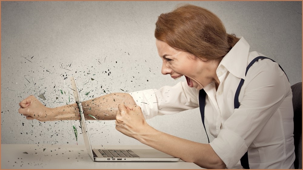 Angry woman punching through her laptop monitor.