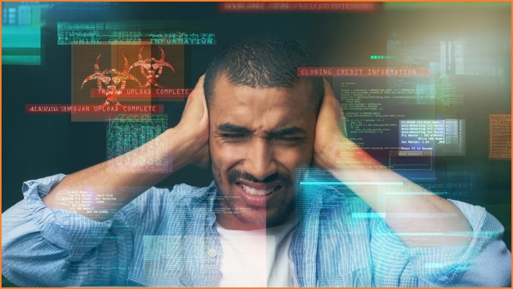 Man holding his hands over his ears, with cyber security related graphics floating around his head.