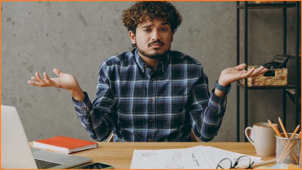 Man sitting at computer, shrugging.