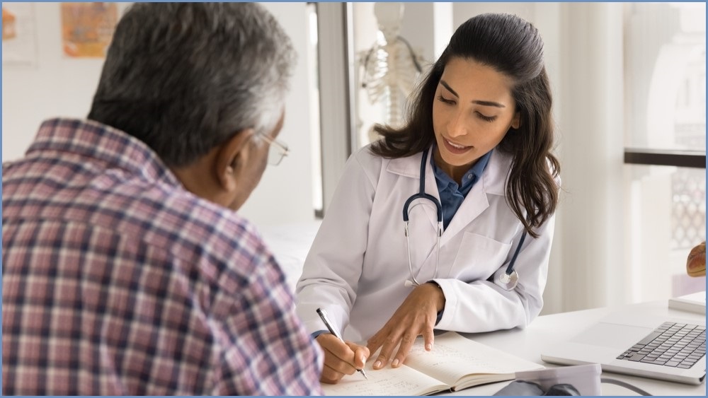 Female doctor taking down notes from a male patient.