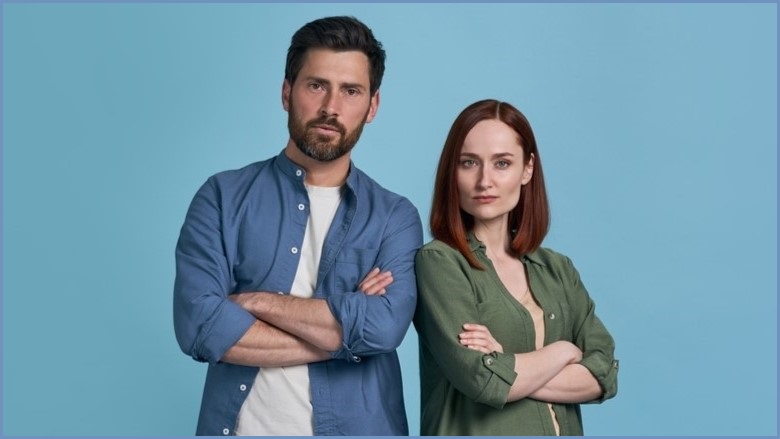 Man and woman with arms folded looking serious.