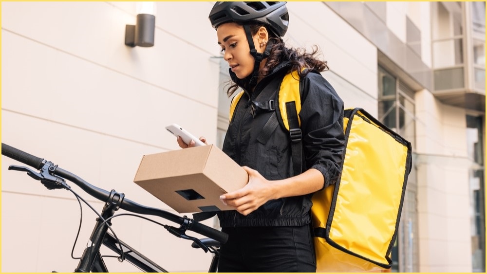 Female delivery worker standing next to a bike.