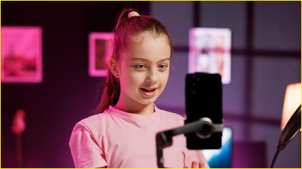 A close up of a tween girl using a mobile phone on a selfie stick, indoors.