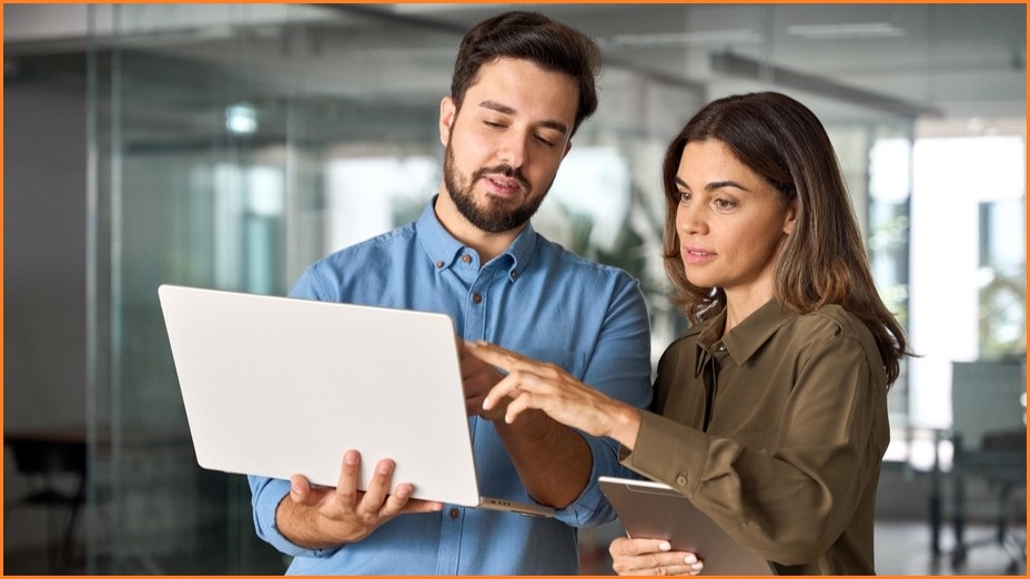 Man and woman pointing at a laptop screen.