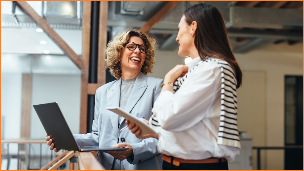 Older woman and younger woman laughing at something on a computer screen.