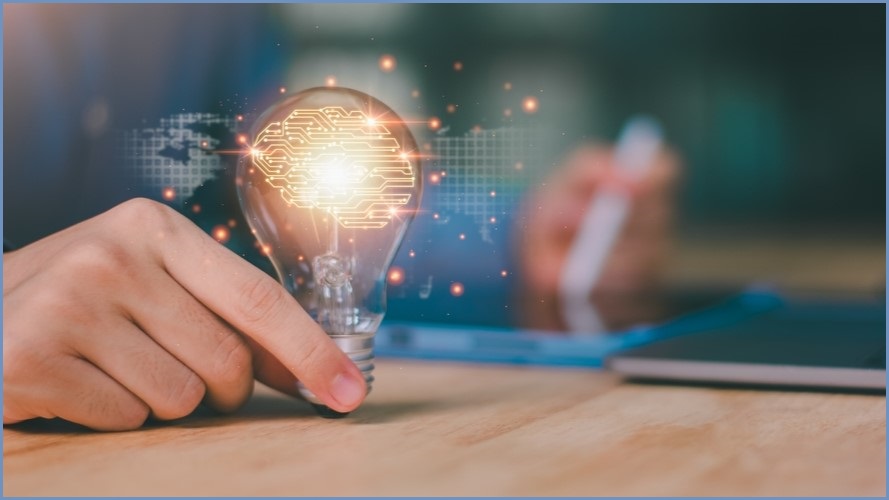 A lit-up light bulb being held upright by a human hand.