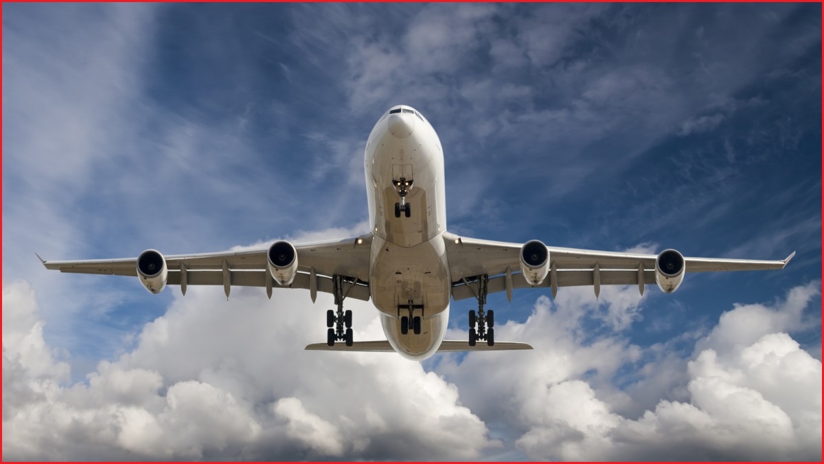 A low-angle wide shot of a large passenger plane flying among the clouds.