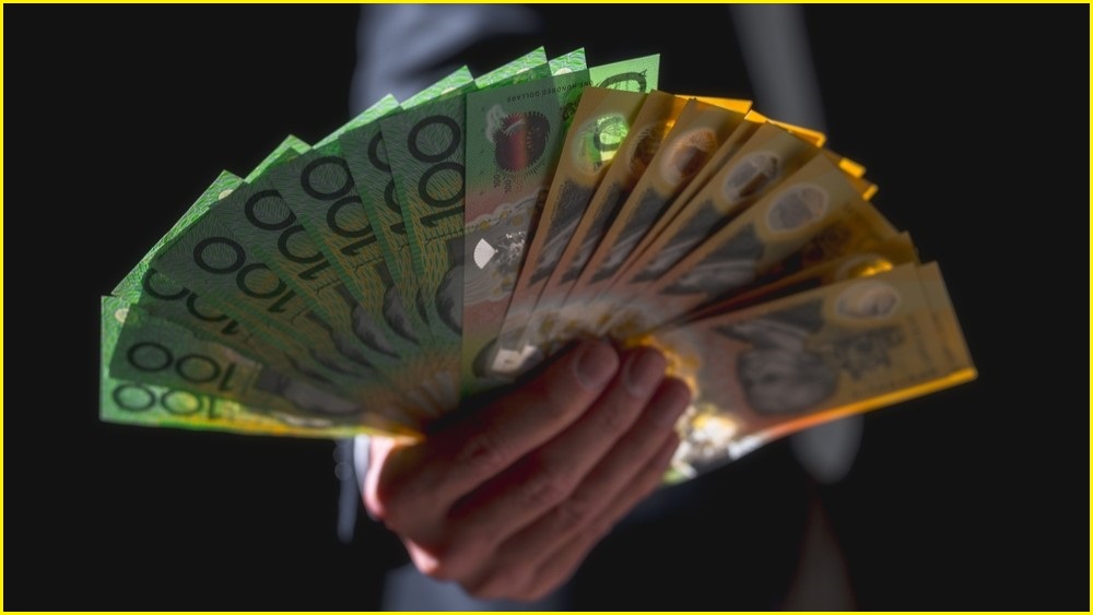 Man holding handful of Austrlaian dollars