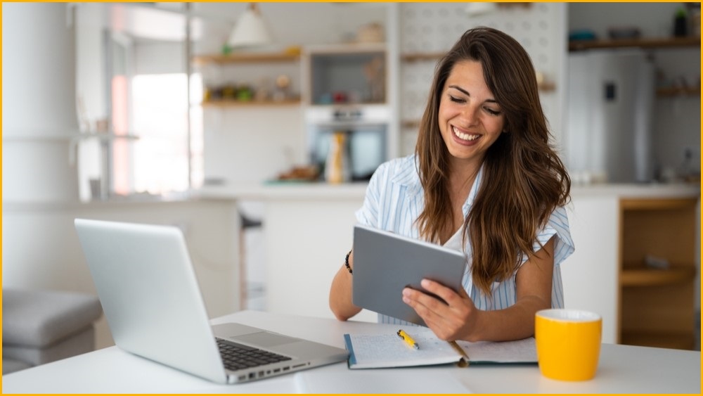 Woman working from home, smiling while using iPad.