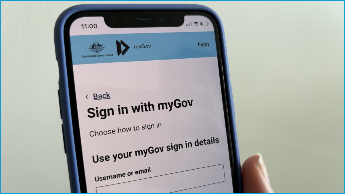 A close up of a hand holding an iPhone displaying the myGov sign in page.