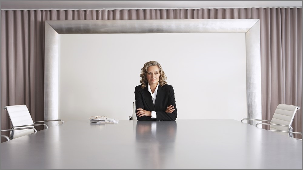 Woman sitting alone at a boardroom table.