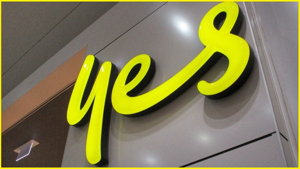A close up on the 'Yes' logo on the wall outside an Optus store.