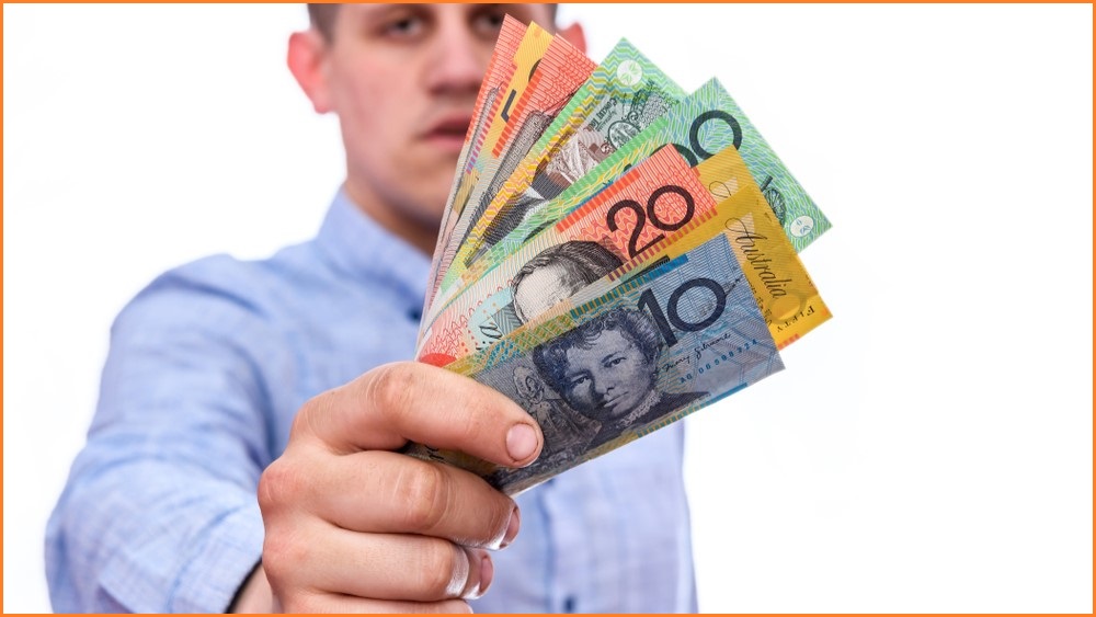 Business man holding out a handful of Australian dollars.