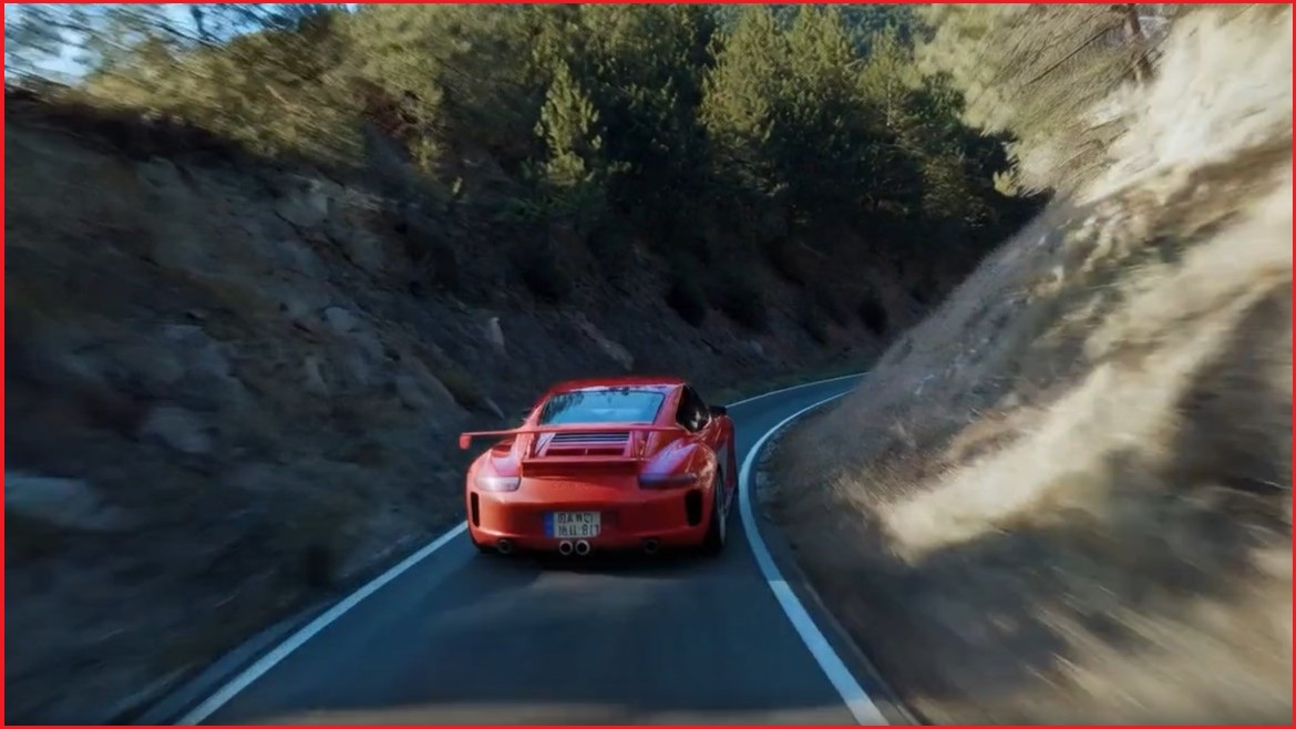 Red porsche driving along the road.