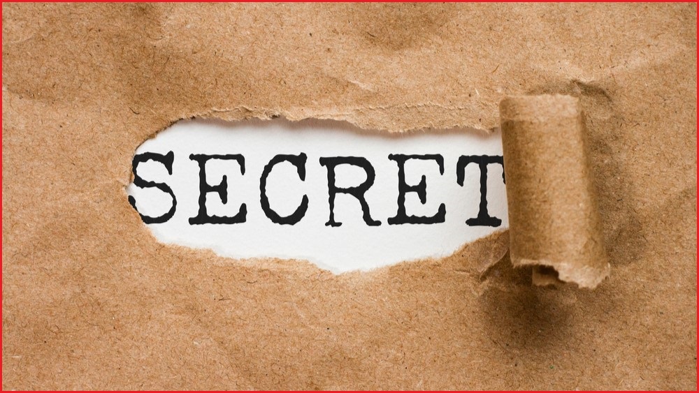 A piece of brown paper ripped back to reveal the word SECRET.