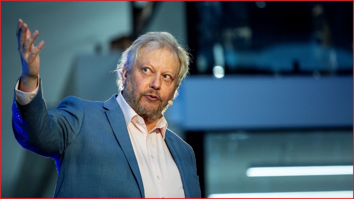 A close up of a middle-aged man in a shirt and suit jacket speaking and gesturing with one hand